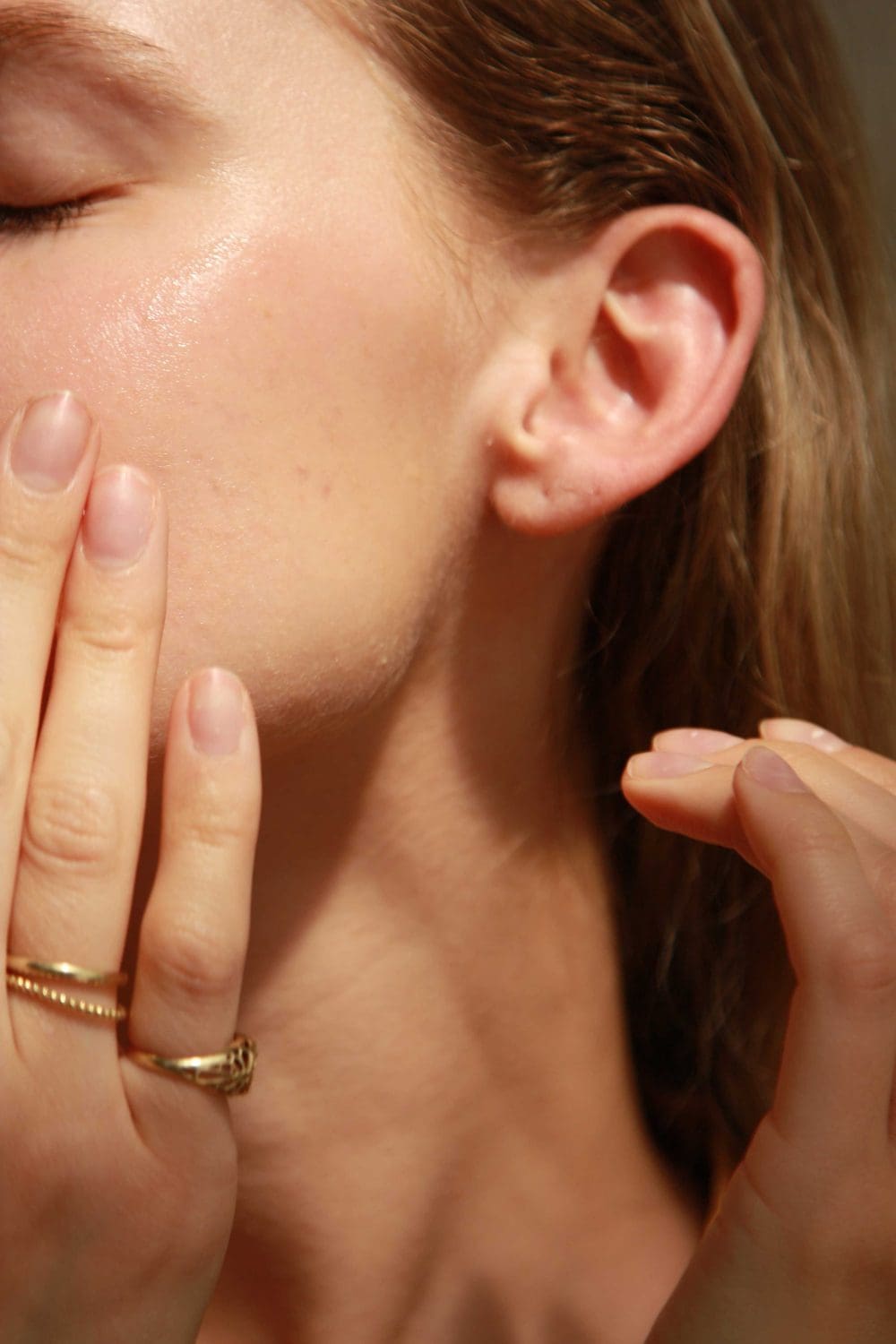 Vrouw raakt haar wang aan en brengt product van emerginC aan